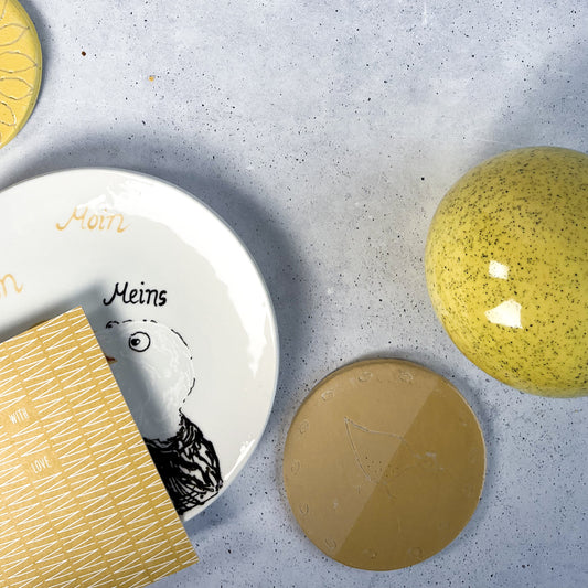 BOTZ engober. 9043 Gold Ochre på den ockrafärgade provplattan nere till höger. Vit lera, bränd vid 1050 °C. Övriga föremål visar andra färger.