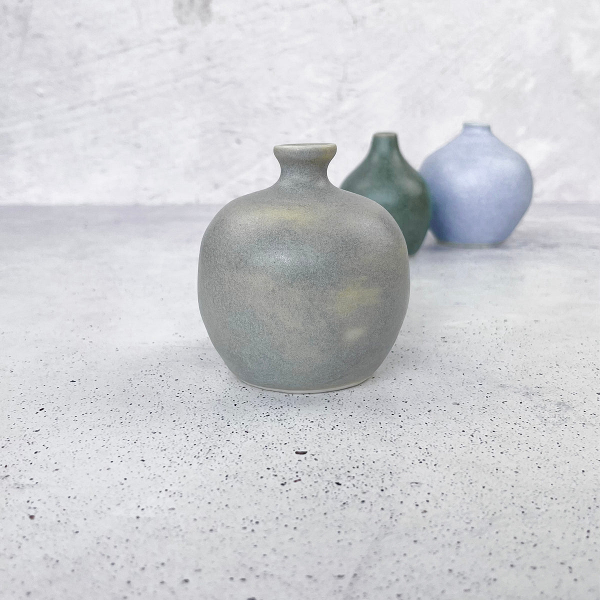 BOTZ 9861 Concrete Grey på den främre vasen vid 1250 °C. Gruppbild med fler alster.