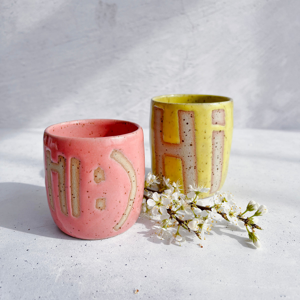 Mugg med BOTZ 9871 Bright yellow på prickig lera vid 1250 °C. Bilden visar även en annan mugg.