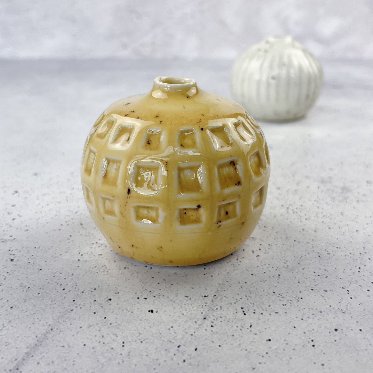 BOTZ 9318 Calcite Yellow PRO. 9318 på den gula vasen i förgrunden, vit lera bränd vid 1250 °C. Den lilla vasen bakom visar ett annat resultat.