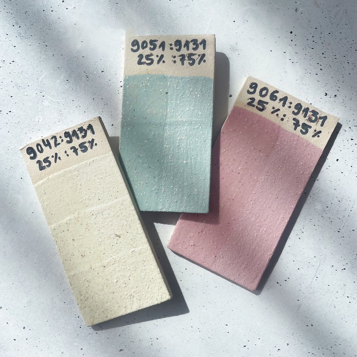 BOTZ engober. Tre märkta blandningsprov: 9042 Yellow, 9051 Dark Green och 9061 Red, vardera 25 % engobe och 75 % 9131 White Glimmer, vid 1050 °C.