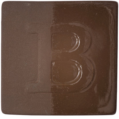 BOTZ engober. BOTZ:s provplatta med 9052 Dark Brown. Vänsterhalvan visar oglaserad engobe; högerhalvan visar samma engobe med ett tunt lager transparent glasyr.