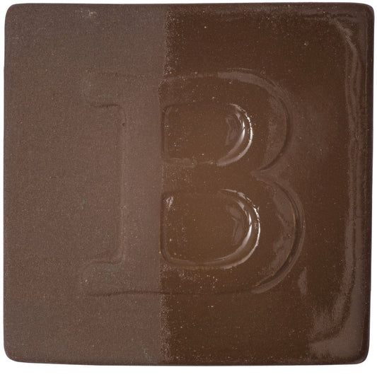 BOTZ engober. BOTZ:s provplatta med 9052 Dark Brown. Vänsterhalvan visar oglaserad engobe; högerhalvan visar samma engobe med ett tunt lager transparent glasyr.