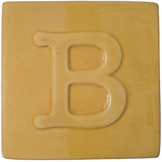 BOTZ engober. BOTZ:s provplatta med 9043 Gold Ochre. Vänsterhalvan visar oglaserad engobe; högerhalvan visar samma engobe med ett tunt lager transparent glasyr.