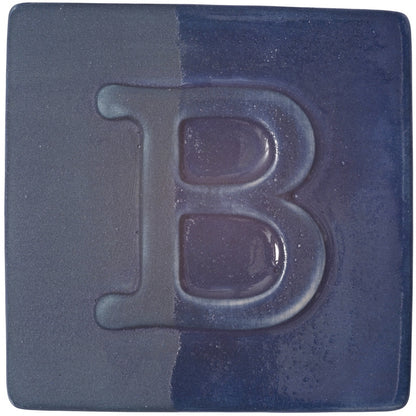 BOTZ engober. BOTZ:s provplatta med 9047 Dark Blue. Vänsterhalvan visar oglaserad engobe; högerhalvan visar samma engobe med ett tunt lager transparent glasyr.